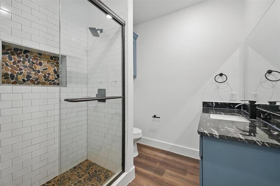 Bathroom featuring vanity, baseboards, toilet, a shower stall, and wood finished floors