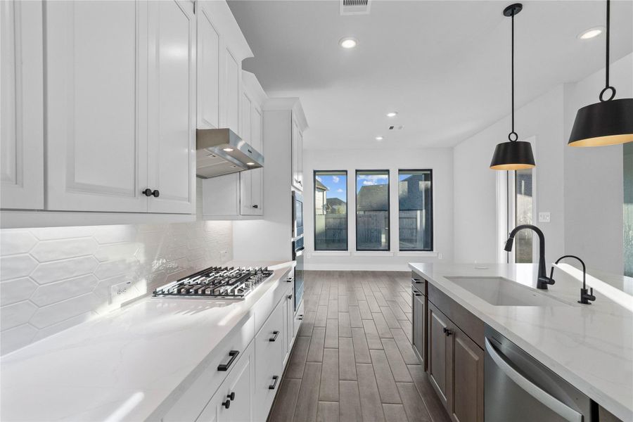 Gourmet kitchen with crisp white shaker cabinetry, stunning quartz countertops, and a sleek tile backsplash
