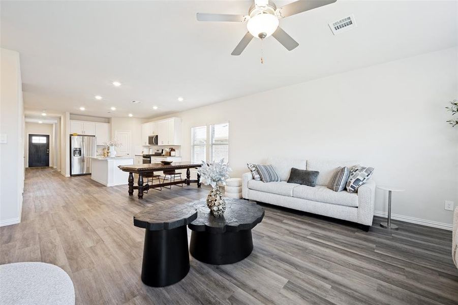 Open-concept living area featuring wood-finish flooring, recessed lighting, and a ceiling fan Open-concept living area featuring wood-finish flooring, recessed lighting, and a ceiling fan