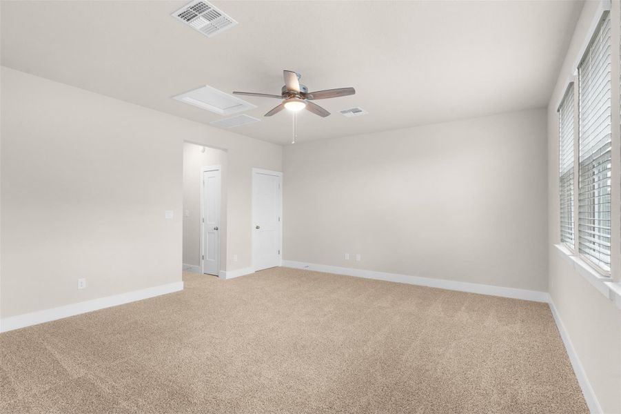 Unfurnished room featuring attic access, light carpet, and ceiling fan