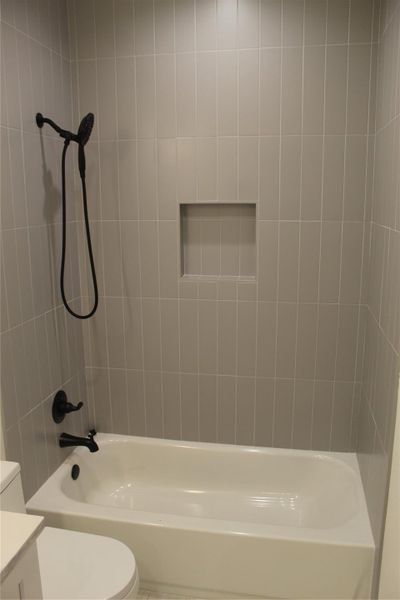 A sleek, tiled bath and shower combo awaits relaxation.