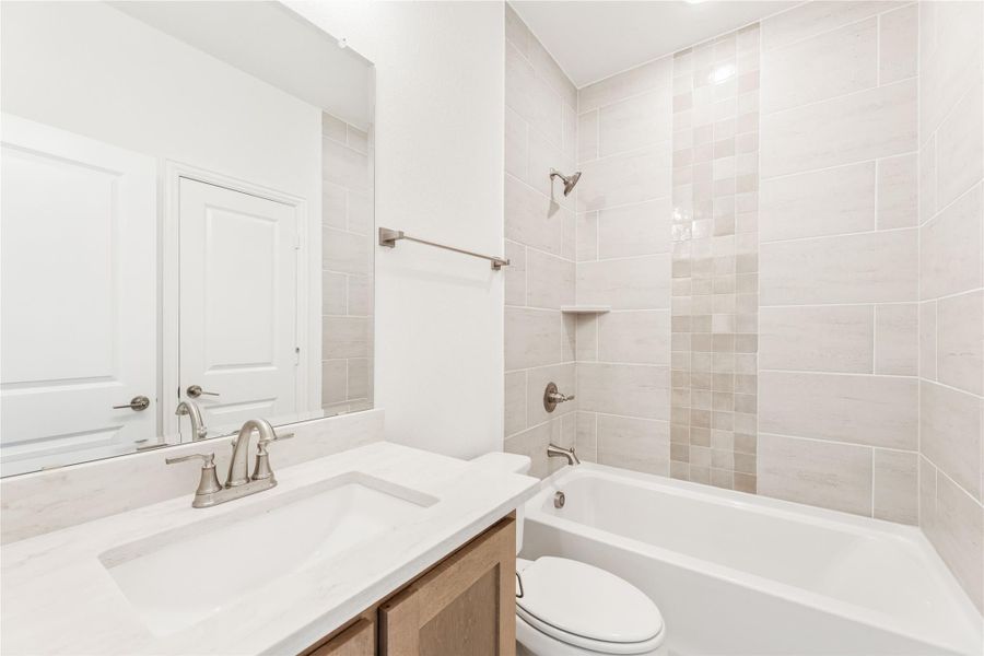 Bathroom with quartz vanity, tub-shower combo, and beige tile surround with brushed nickel fixtures