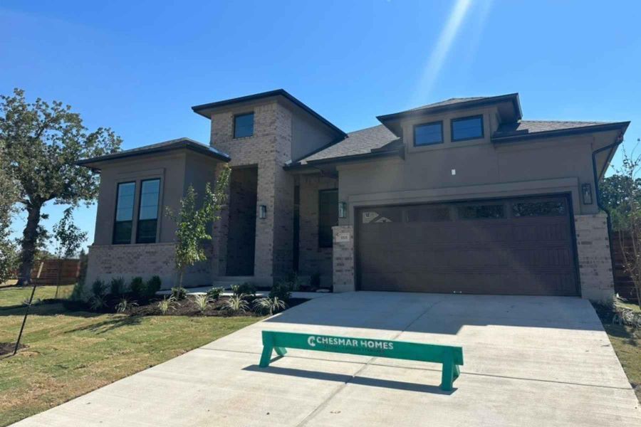View of front of property featuring brick siding, a front lawn, concrete driveway, a garage, and stucco siding View of front of property featuring brick siding, a front lawn, concrete driveway, a garage, and stucco siding