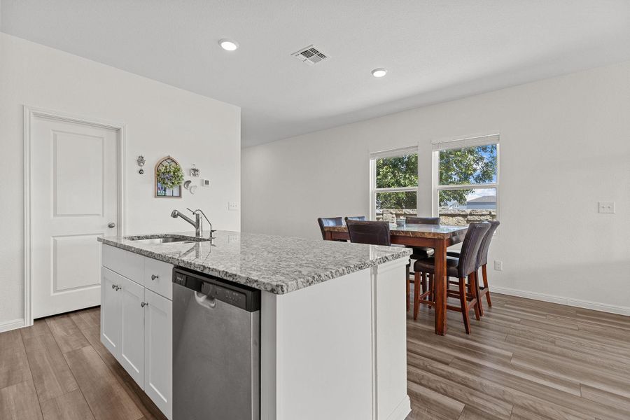 Kitchen with dishwasher, white cabinetry, light stone countertops, an island with sink, and recessed lighting Kitchen with dishwasher, white cabinetry, light stone countertops, an island with sink, and recessed lighting