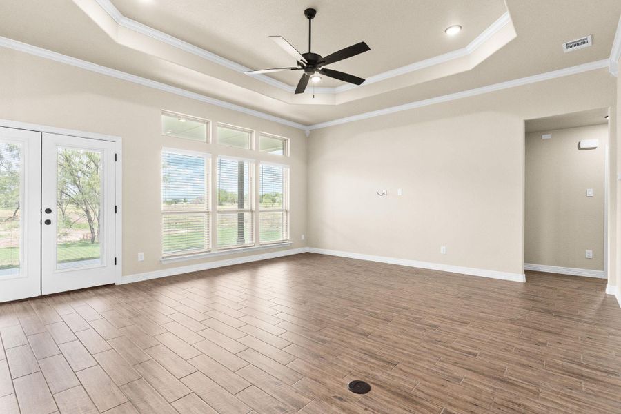 Living room with a tray ceiling, crown molding, wood look tile floors, a ceiling fan, and french doors Living room with a tray ceiling, crown molding, wood look tile floors, a ceiling fan, and french doors