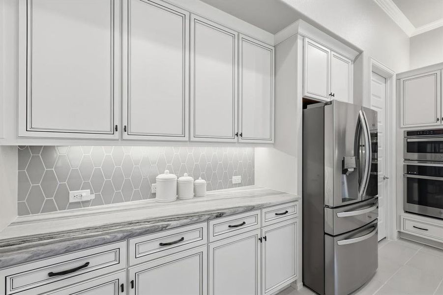 Kitchen featuring white perimeter cabinetry with black hardware, under-cabinet lighting, and a gray hexagonal tile backsplash