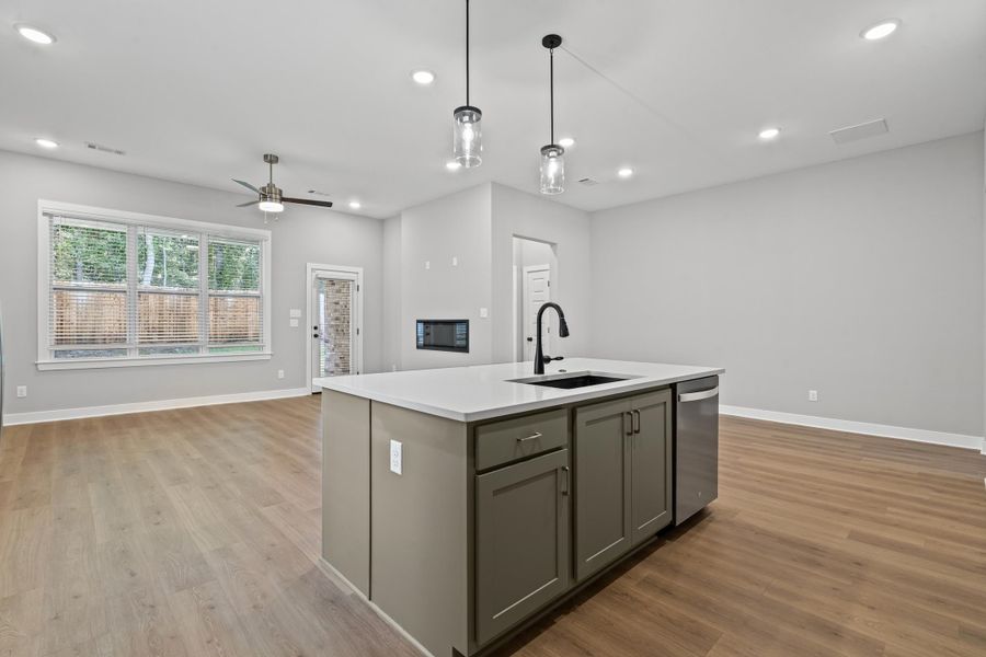 Kitchen with open floor plan, gray cabinets, pendant lighting, a center island with sink, and recessed lighting