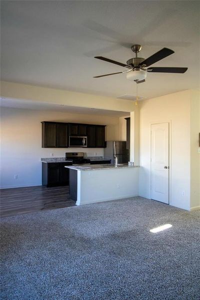 Kitchen with open floor plan, appliances with stainless steel finishes, a ceiling fan, and dark brown cabinets