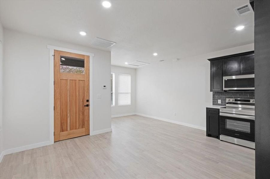 Kitchen with stainless steel appliances, light hardwood / wood-style flooring, and tasteful backsplash