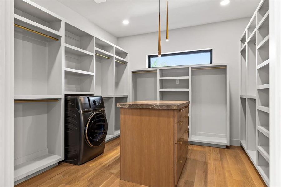 Walk in closet with washer / clothes dryer and light wood finished floors Walk in closet with washer / clothes dryer and light wood finished floors