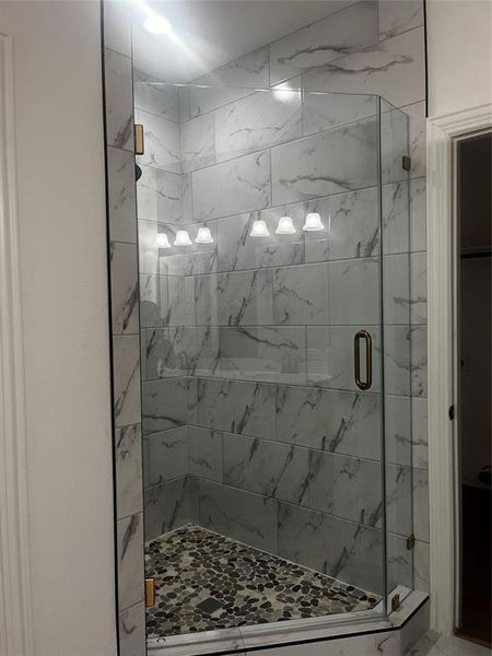 Full bath featuring a marble finish shower Full bath featuring a marble finish shower