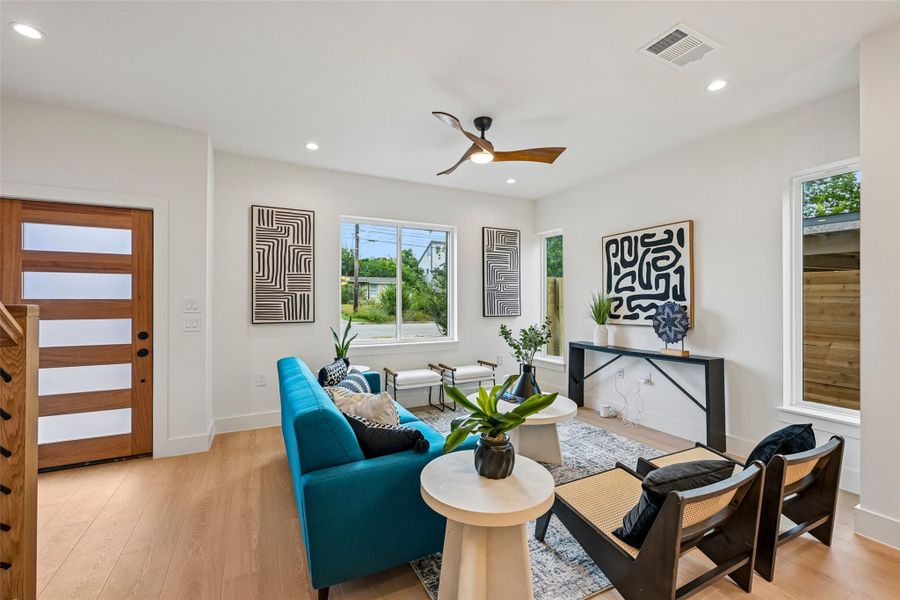 Blonde flooring flow through this sun-filled living room, featuring a modern wood entry door.