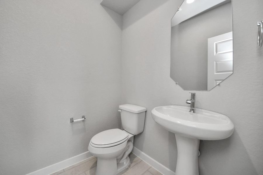 This half bathroom features a stylish pedestal sink, modern hardware, and bright recessed lighting, creating a sleek and inviting space. Sample photo of completed home with similar floor plan. Actual colors and selections may vary.