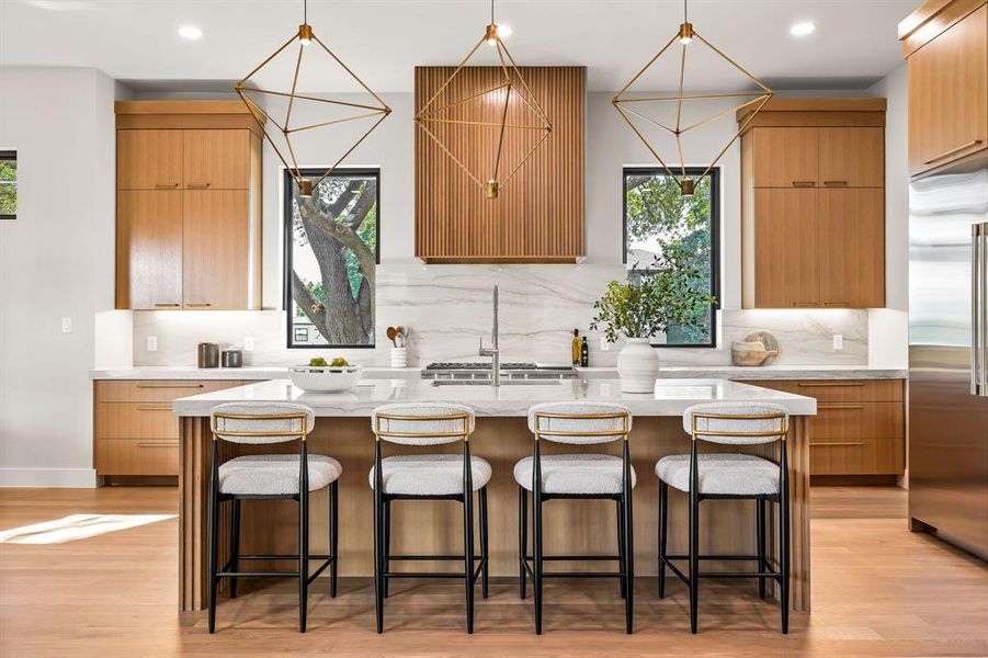 Kitchen featuring healthy amount of natural light, light stone counters, light wood finished floors, a kitchen bar, and recessed lighting Kitchen featuring healthy amount of natural light, light stone counters, light wood finished floors, a kitchen bar, and recessed lighting