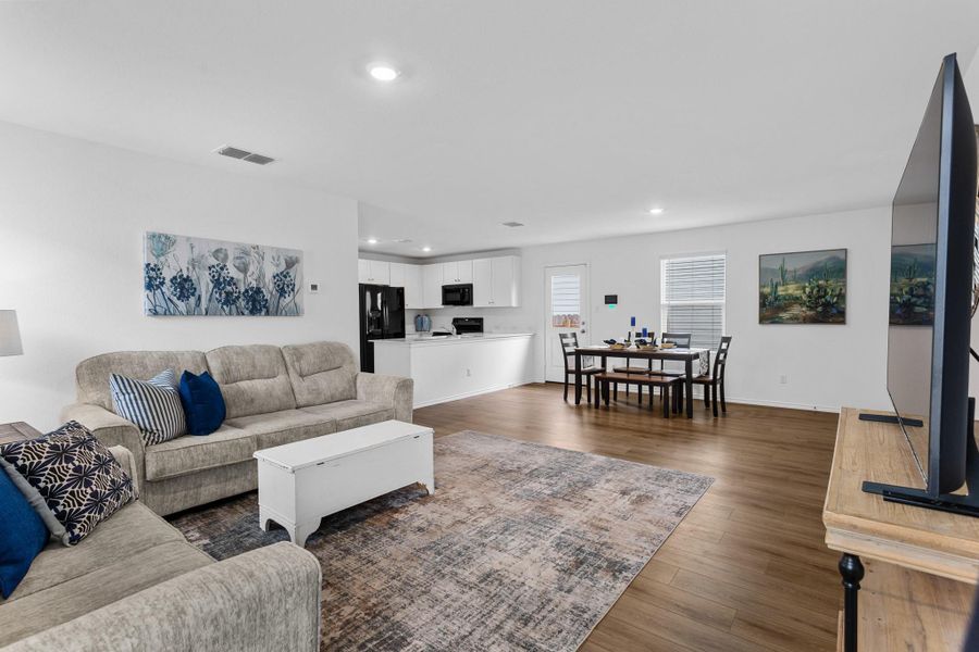 Open-concept living area with wood-finish flooring, white walls, and recessed lighting