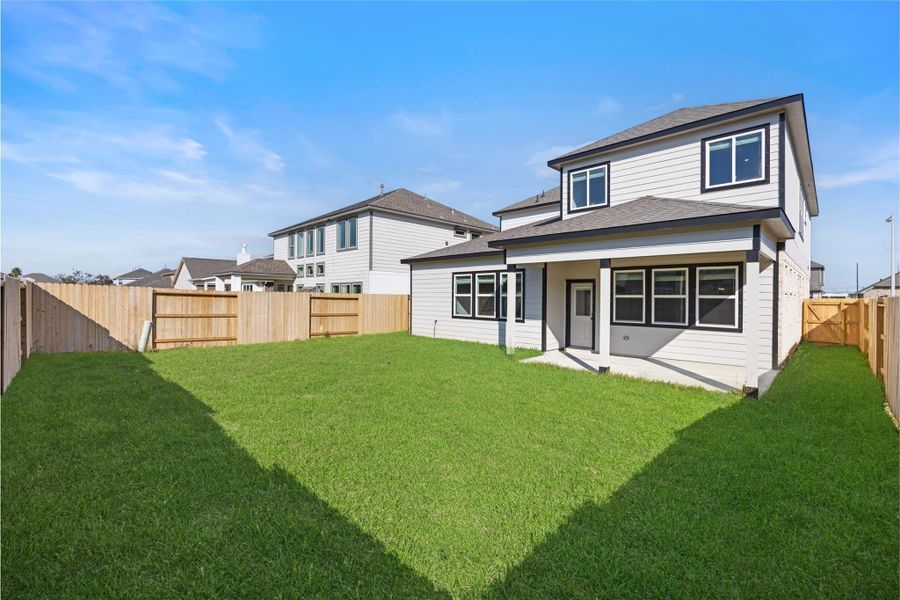 This photo showcases the backyard of a two-story house with a well-maintained lawn, a wooden fence for privacy, and a covered patio area, perfect for outdoor activities and relaxation. This photo showcases the backyard of a two-story house with a well-maintained lawn, a wooden fence for privacy, and a covered patio area, perfect for outdoor activities and relaxation.