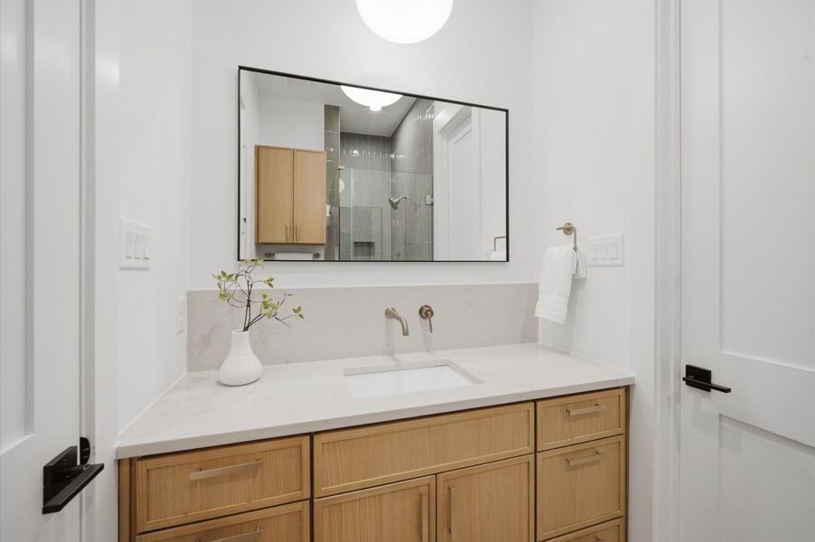 Bathroom vanity with quartz countertop and white oak cabinetry.