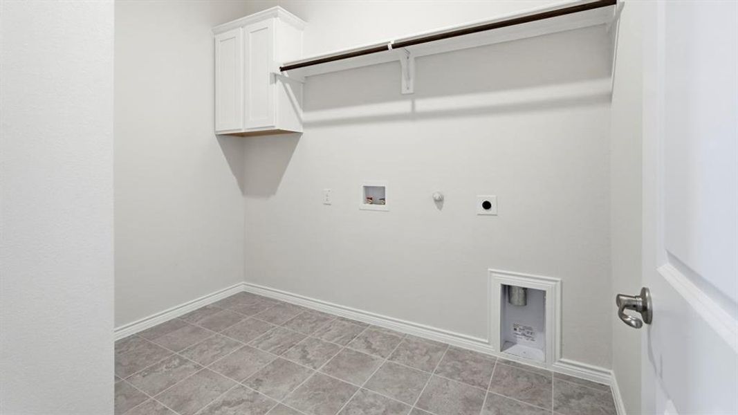 Laundry room with gas dryer hookup, washer hookup, cabinet space, and light tile patterned floors Laundry room with gas dryer hookup, washer hookup, cabinet space, and light tile patterned floors