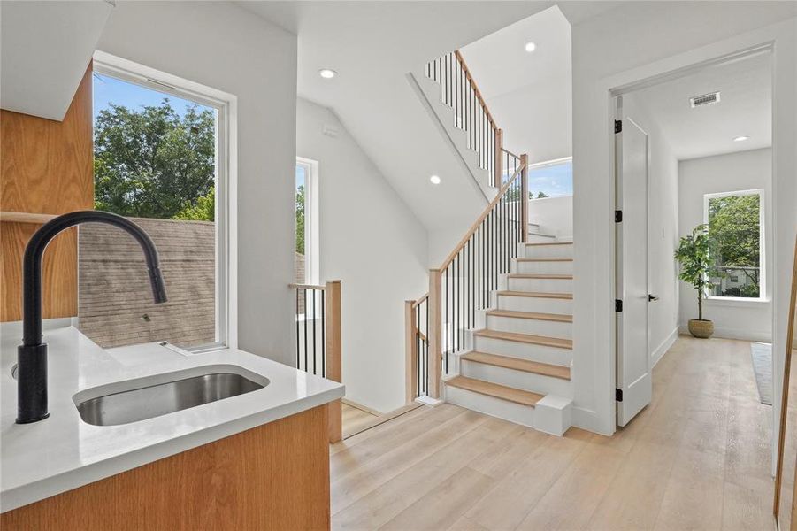 Wet-Bar featuring sink, light wood-type flooring, and vaulted ceiling