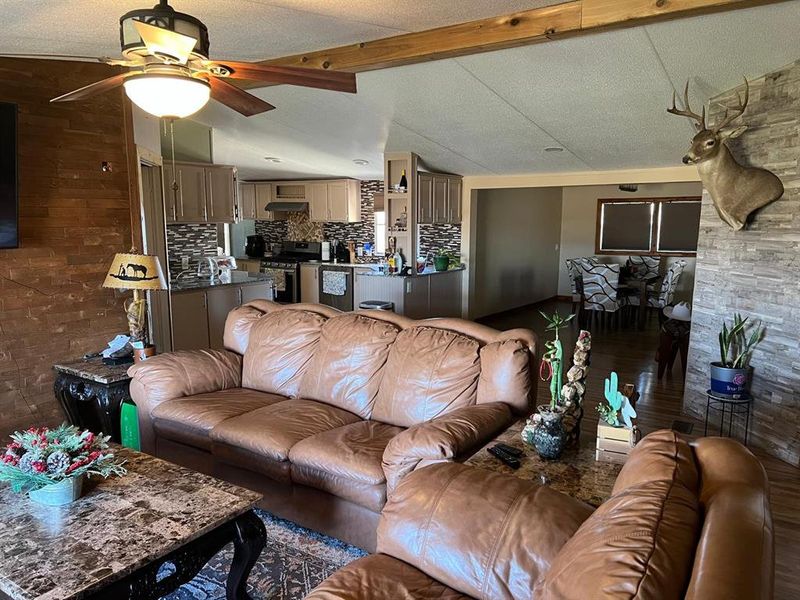 Living room featuring vaulted ceiling with beams, ceiling fan, and dark hardwood / wood-style flooring