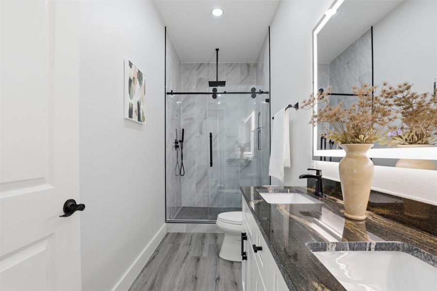 Bathroom featuring a dual vanity with undermount sinks and a dark, veined countertop