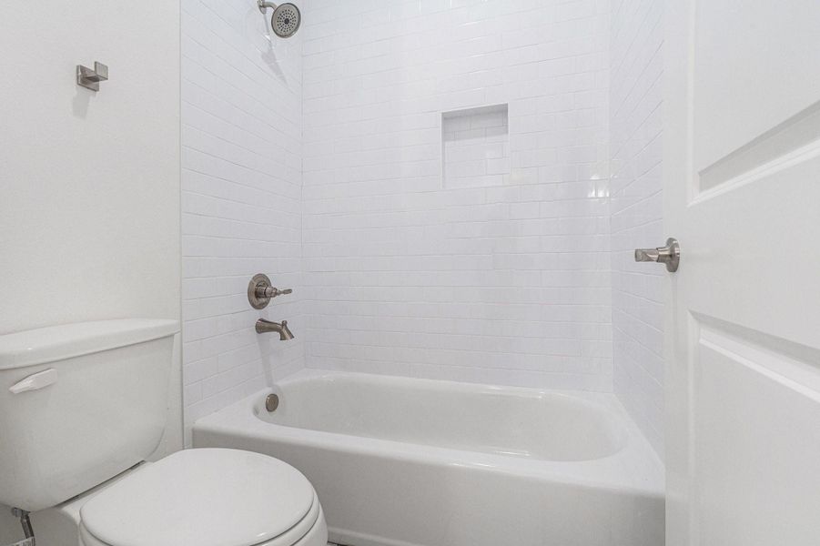This bathroom features a clean, modern design with white subway tiles, a built-in shower niche, and brushed nickel fixtures. It includes a classic bathtub and a toilet, offering a fresh and simple aesthetic. This bathroom features a clean, modern design with white subway tiles, a built-in shower niche, and brushed nickel fixtures. It includes a classic bathtub and a toilet, offering a fresh and simple aesthetic.