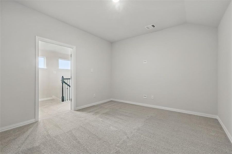 Empty room with carpet and lofted ceiling Empty room with carpet and lofted ceiling