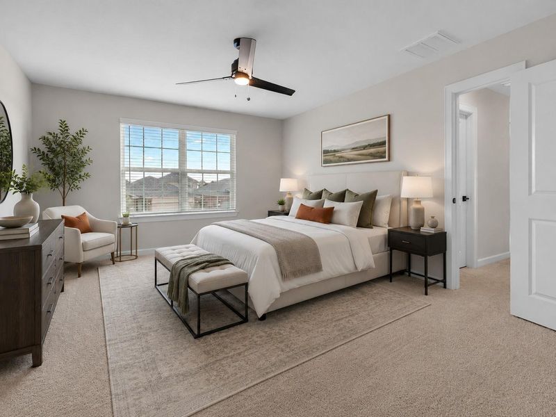 Spacious primary suite featuring soft carpeting, a large window, ceiling fan, and direct access to the ensuite bath and walk-in closet.**Virtually staged Spacious primary suite featuring soft carpeting, a large window, ceiling fan, and direct access to the ensuite bath and walk-in closet.**Virtually staged