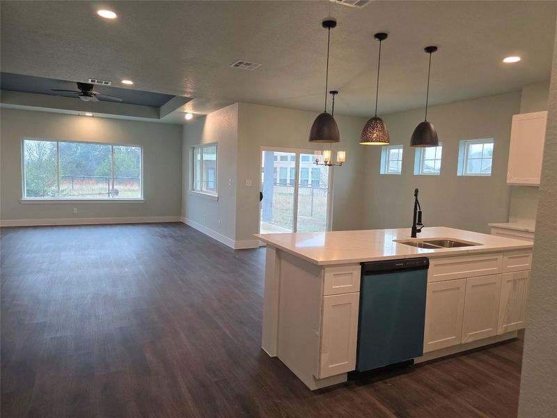 Kitchen featuring white cabinets, recessed lighting, dishwashing machine, dark wood-style floors, and a center island with sink