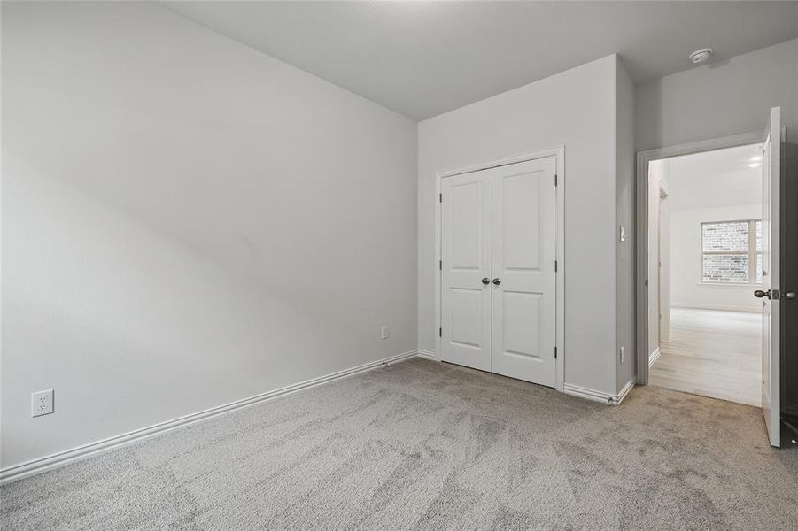 Unfurnished bedroom featuring light carpet and a closet