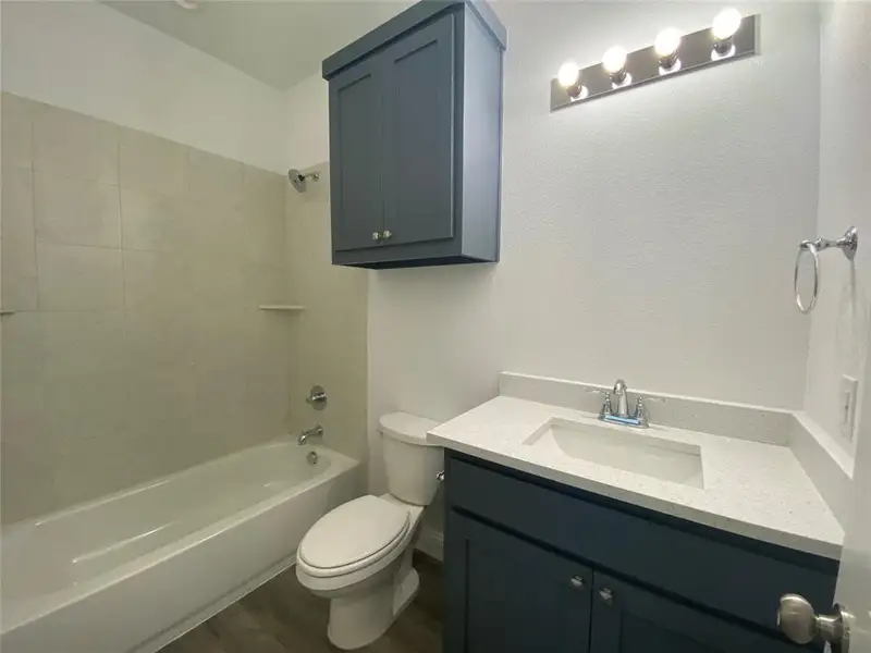 Bathroom featuring dark wood-style flooring, vanity, and shower combination Bathroom featuring dark wood-style flooring, vanity, and shower combination