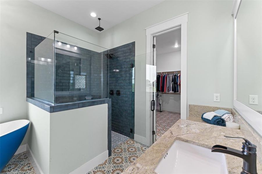 Bathroom featuring a walk-in shower with glass enclosure, blue subway tile, and a rainfall showerhead
