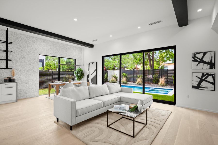 Living area featuring beam ceiling, light wood-style flooring, recessed lighting, and an accent wall