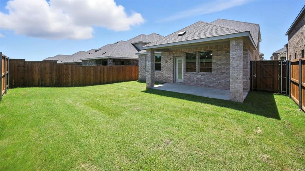 Rear view of house featuring brick siding, a patio, a gate, a fenced backyard, and roof with shingles Rear view of house featuring brick siding, a patio, a gate, a fenced backyard, and roof with shingles
