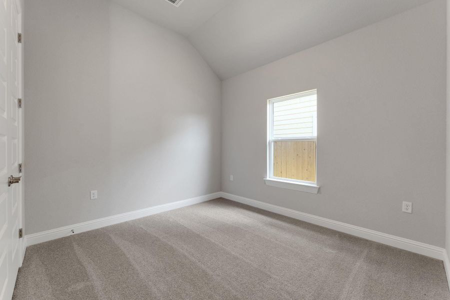 Carpeted spare room with vaulted ceiling and baseboards Carpeted spare room with vaulted ceiling and baseboards