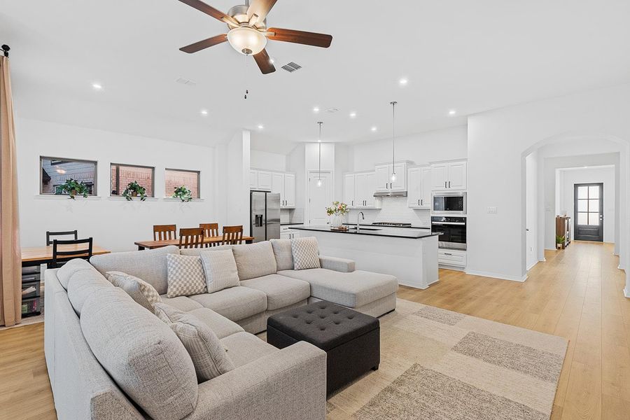 Living area featuring light wood finished floors, recessed lighting, arched walkways, and a ceiling fan