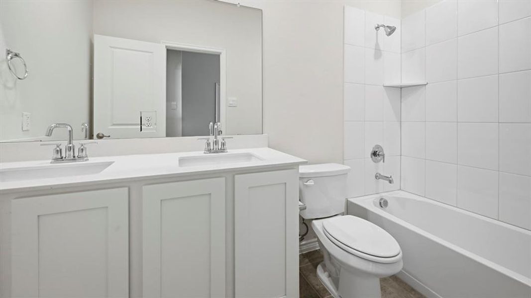 Bathroom featuring a dual vanity with white cabinetry, integrated sinks, and chrome fixtures Bathroom featuring a dual vanity with white cabinetry, integrated sinks, and chrome fixtures