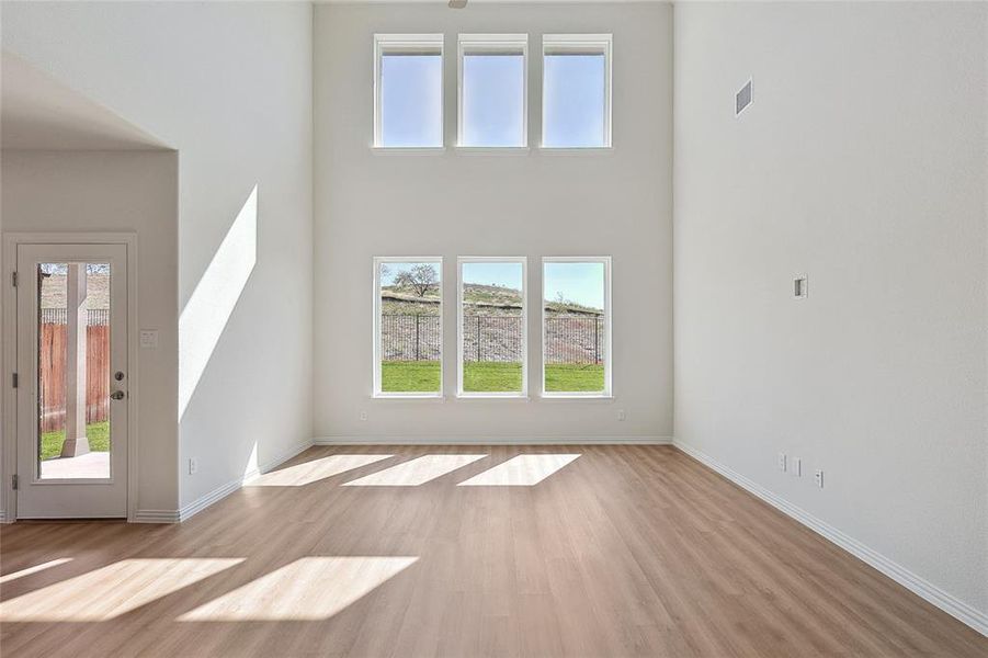 Unfurnished living room featuring light hardwood / wood-style flooring and a high ceiling