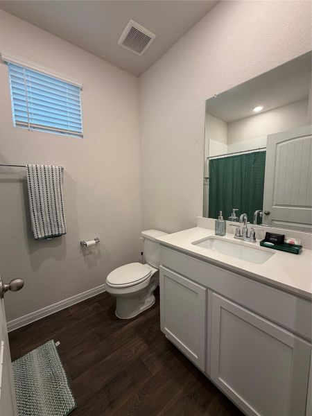 Bathroom featuring a shower with shower curtain, vanity, and dark wood-type flooring