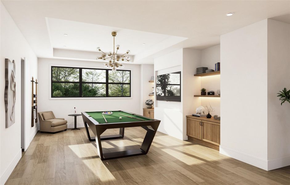 A spacious game room concept featuring floor-to-ceiling windows that invite natural light across warm wood floors. The area offers a flexible layout with a striking chandelier, custom shelving, and space for future entertainment options like a billiards table or lounge seating, an ideal setup for gathering or relaxing.
