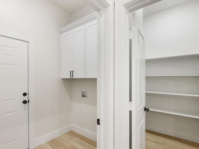 Laundry area featuring light wood-style floors, washer hookup, and cabinet space