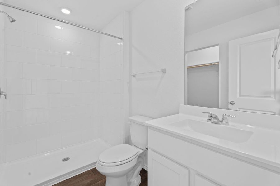 Bathroom featuring vanity, toilet, wood finished floors, and a tile shower Bathroom featuring vanity, toilet, wood finished floors, and a tile shower