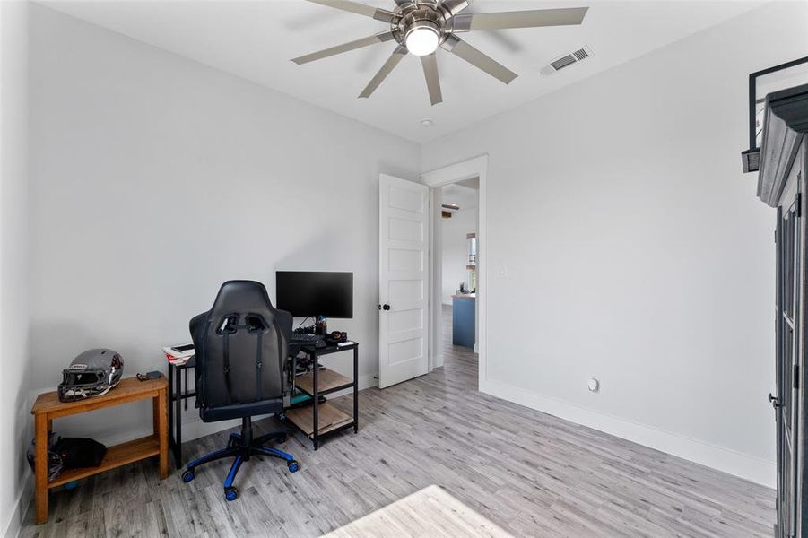 Interior room featuring light wood-finish flooring, crisp white walls, and a contemporary ceiling fan with integrated lighting
