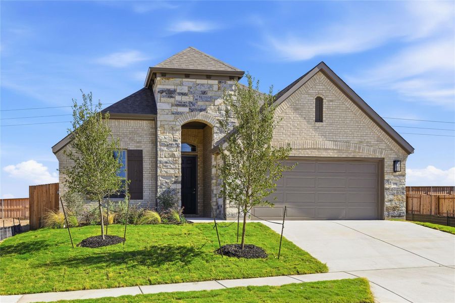 French provincial home featuring stone siding, brick siding, driveway, and roof with shingles