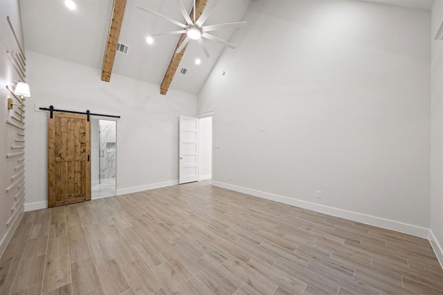 Spacious room featuring vaulted ceilings with exposed wood beams, wood-finish tile flooring, and recessed lighting Spacious room featuring vaulted ceilings with exposed wood beams, wood-finish tile flooring, and recessed lighting