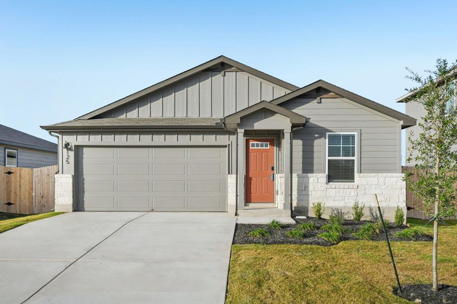 View of front of house featuring board and batten siding, concrete driveway, stone siding, and a garage