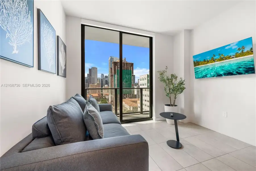 Floor-to-ceiling glass sliding door, balcony access, tile flooring, and urban cityscape backdrop Floor-to-ceiling glass sliding door, balcony access, tile flooring, and urban cityscape backdrop