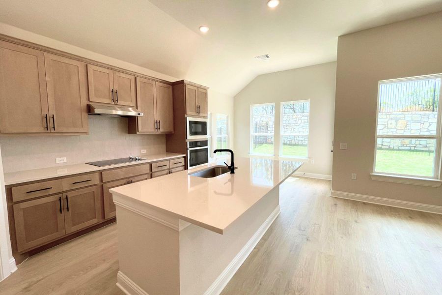 Recessed lighting illuminates this kitchen featuring a central island, modern cabinetry, and light wood flooring. Recessed lighting illuminates this kitchen featuring a central island, modern cabinetry, and light wood flooring.