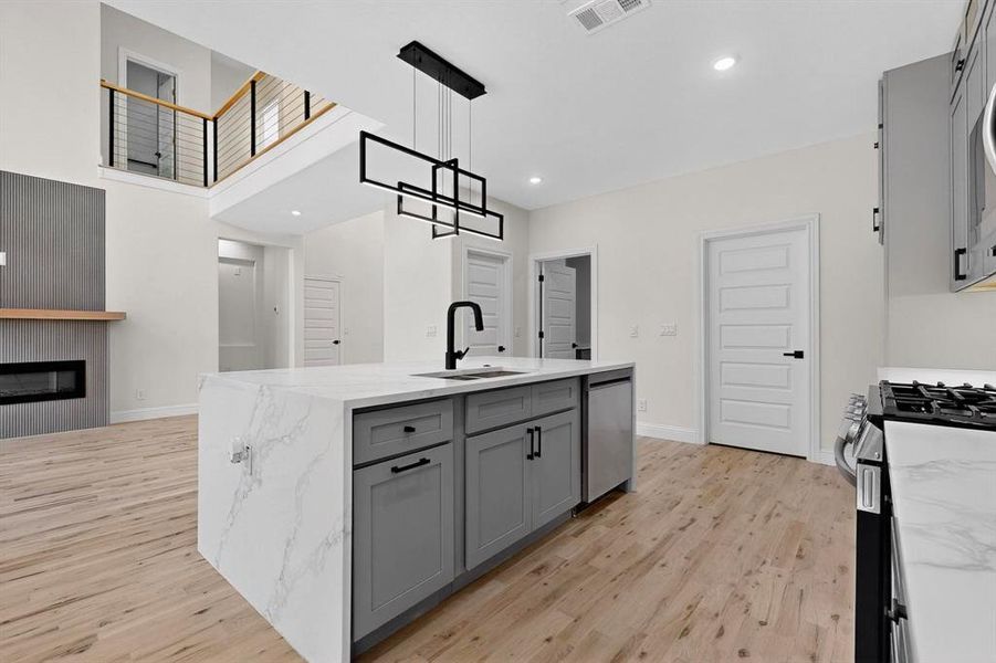 Kitchen with gray cabinets, pendant lighting, light stone counters, appliances with stainless steel finishes, and recessed lighting Kitchen with gray cabinets, pendant lighting, light stone counters, appliances with stainless steel finishes, and recessed lighting