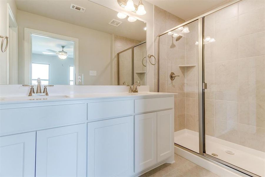 Bathroom featuring ceiling fan, tile patterned floors, vanity, and a shower with shower door